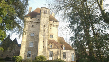 L’image montre un grand bâtiment historique en pierre avec une tour proéminente, ressemblant à un château ou un manoir. 